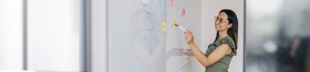 Mitarbeiterin des Marketing zeigt auf das Whiteboard