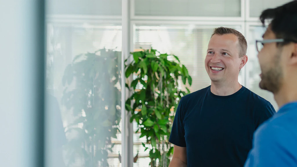 Mitarbeiter in der Softwareentwicklung lächeln und schauen dabei auf ein Whiteboard