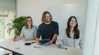 Mitarbeiter in der Softwareentwicklung lächeln und arbeiten am Tablet