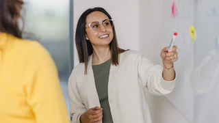 Mitarbeiterin des Marketing zeigt auf das Whiteboard