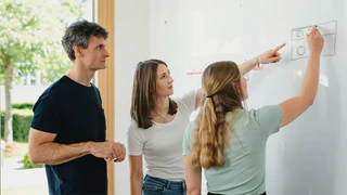 Mitarbeiter zeigen auf Whiteboard