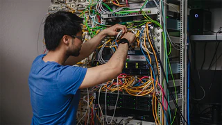 Mitarbeiter der IT steckt Kabel an