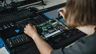 Mitarbeiter der IT bestückt elektronische Bauteile auf einer Platine
