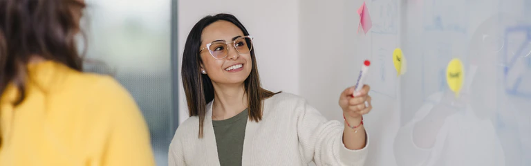 Mitarbeiterin des Marketing zeigt auf das Whiteboard