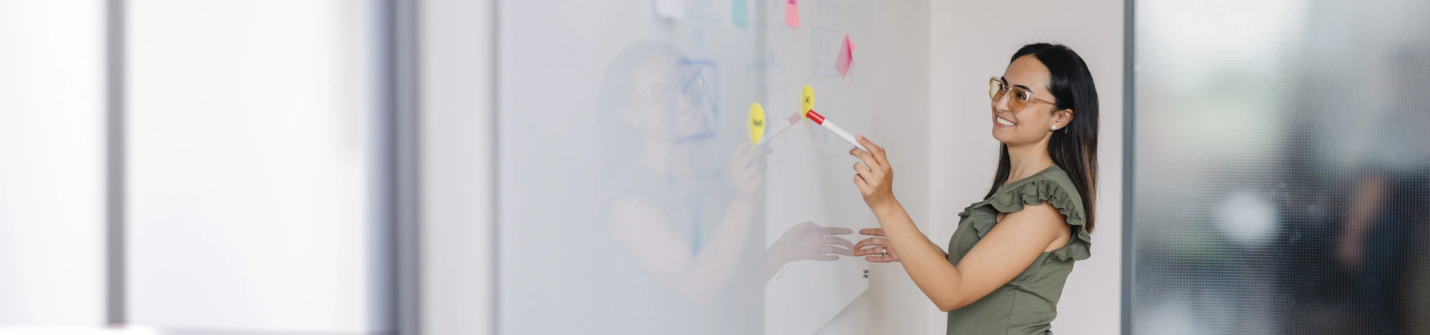 Mitarbeiterin des Marketing zeigt auf das Whiteboard