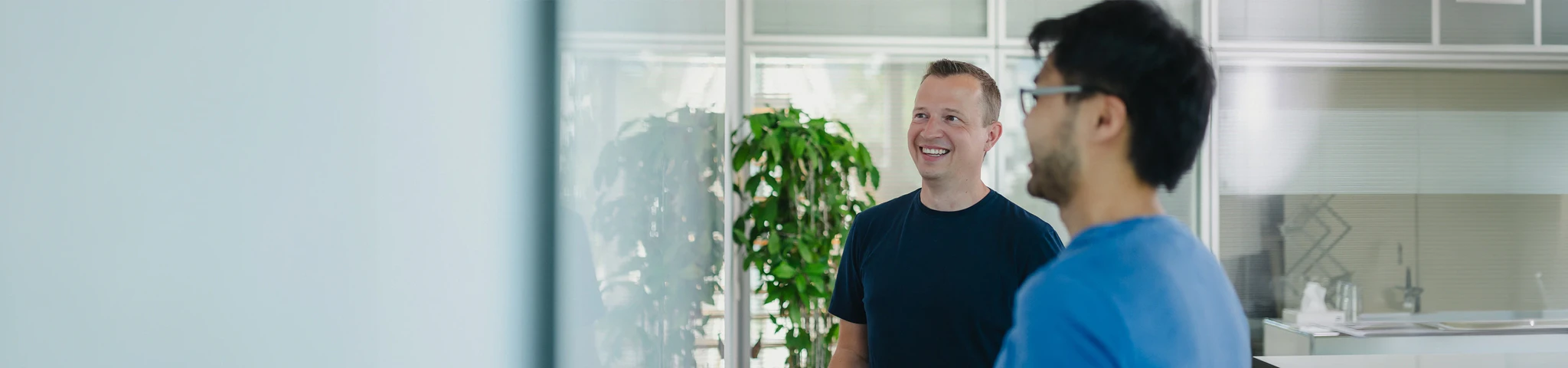 Mitarbeiter in der Softwareentwicklung lächeln und schauen dabei auf ein Whiteboard